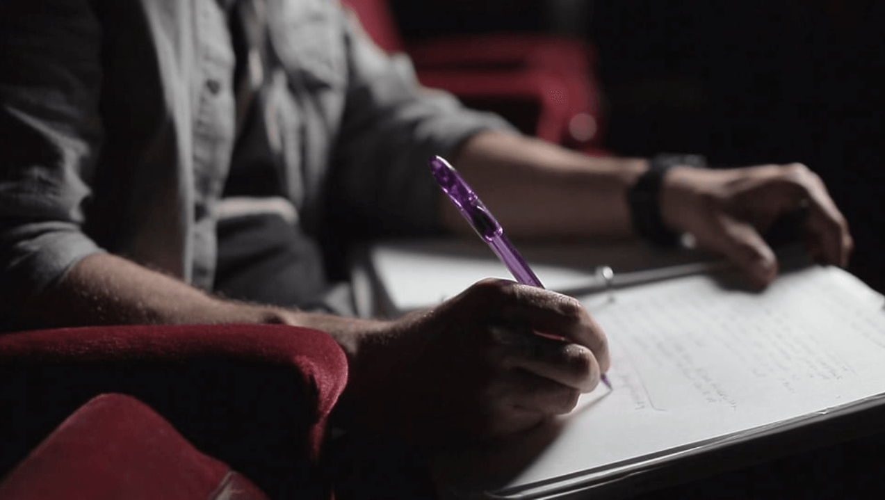 man writing notes on paper